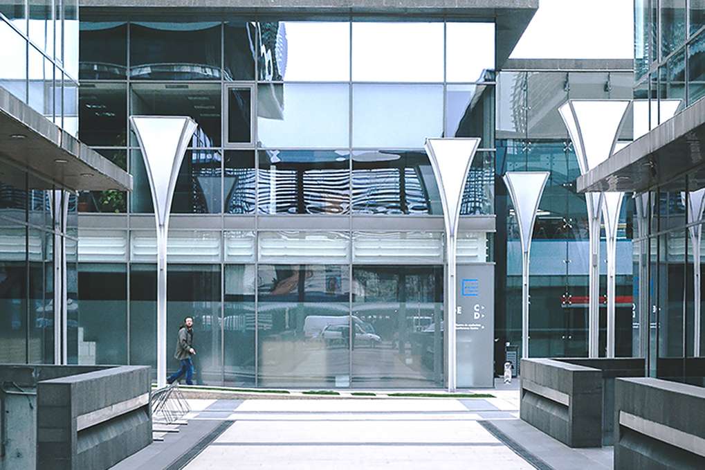 Na tym obrazku widoczny jest imponujący budynek wykonany ze szkła, który emanuje nowoczesnością i przepychającą elegancją. Transparentne ściany ze szkła zapewniają widok na wnętrze, tworząc połączenie między architekturą a otoczeniem. Ten unikalny design sprawia, że budynek staje się prawdziwą atrakcją, przyciągającą wzrok i zachwycającą swoją przejrzystością